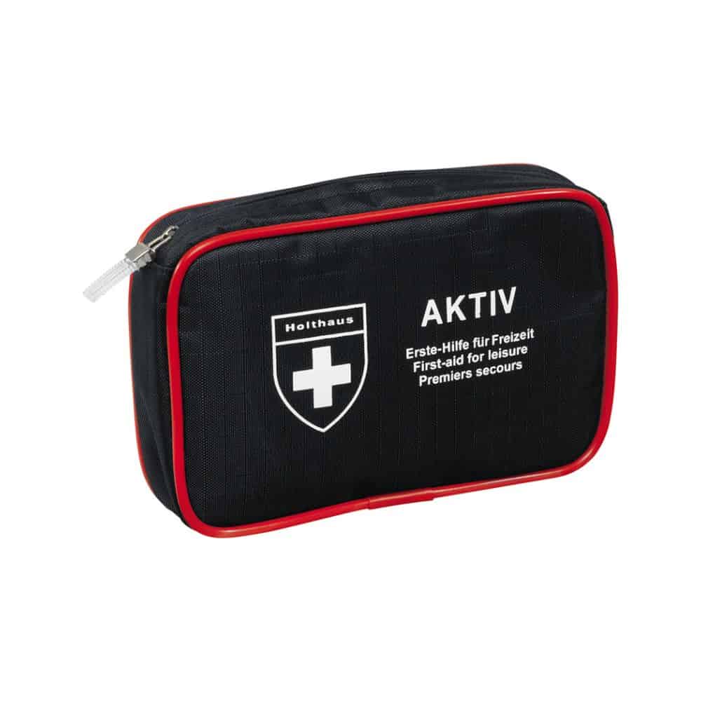 Un kit de premiers secours compact noir avec garniture rouge et fermeture éclair, un logo croix blanc et les textes « Holthaus Medical AKTIV » et « Erste-Hilfe für Freizeit / First-aid for Leisure / Premiers secours » sur le devant. Parfait pour les déplacements et à la maison.