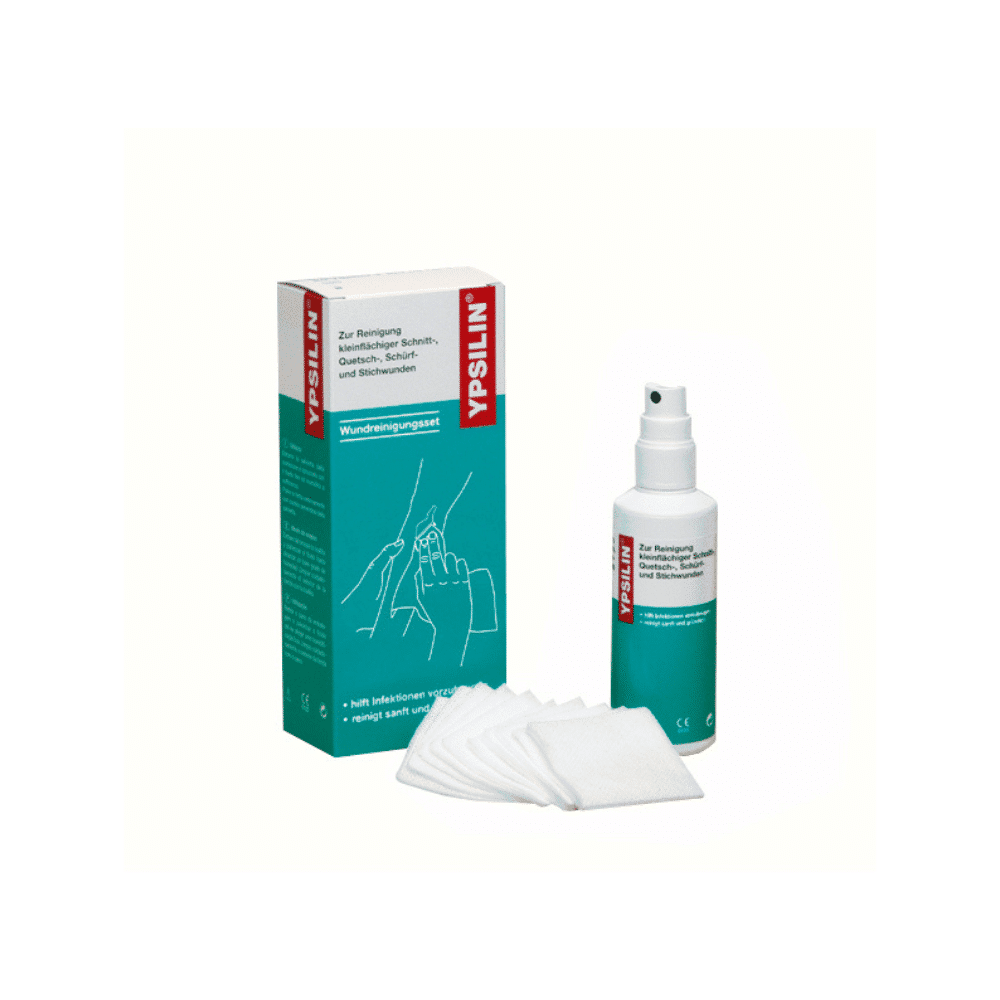 Le kit de nettoyage des plaies YPSILIN® de Holthaus Medical de Holthaus Medical GmbH & Co. KG comprend une boîte, une bouteille et plusieurs compresses de gaze. Tant la boîte que la bouteille ont un fond blanc avec des accents bleu-vert et rouges et portent l'inscription allemande « YPSILIN ». La bouteille Holthaus Medical est équipée d'une buse de pulvérisation, tandis que les compresses de gaze sont des carrés blancs destinés au nettoyage des plaies.