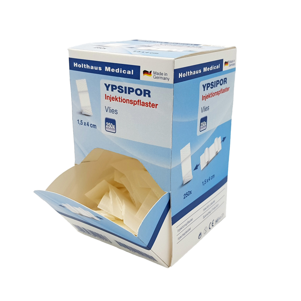 Une boîte rectangulaire de pansements d'injection Holthaus Ypsipor de Holthaus Medical GmbH & Co. KG avec l'inscription « Made in Germany ». La boîte est principalement bleu clair et blanche, mesure 1,5 x 4 cm, contient 250 pansements en non-tissé avec coussinet absorbant et est représentée avec le rabat supérieur ouvert, révélant le contenu.