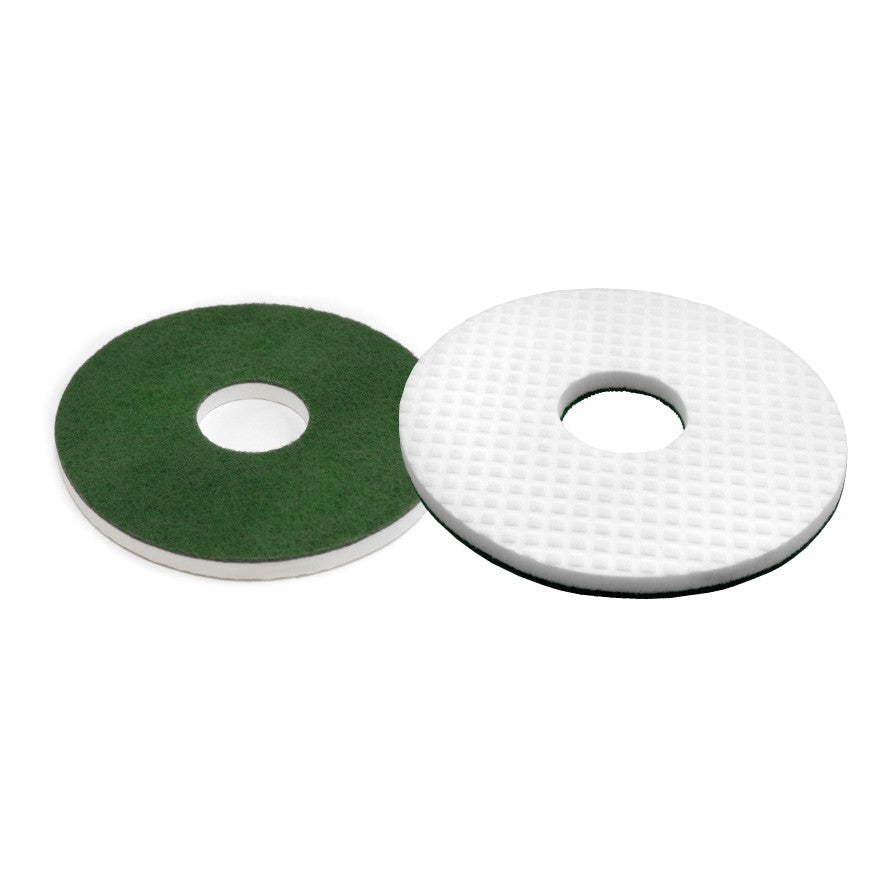 Illustrés sont deux tampons de sol ronds : un tampon vert avec une surface lisse et le Arcora MELAMIN RUNDPAD de Arcora International GmbH avec une surface blanche, texturée et en forme de grille. Les deux ont un trou central pour le nettoyage professionnel.