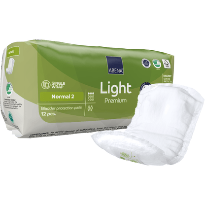 Un paquet vert et blanc ABENA Light Normal 2, Premium | Packung (12 pièces) de la Abena Re-Seller GmbH se trouve à côté d'une protection non pliée. L'emballage affiche les détails du produit, des symboles et met en avant la capacité d'absorption.