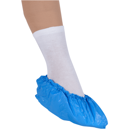 Un pied dans une chaussette blanche est protégé par une surchaussure bleue Abena Re-Seller GmbH, 15 cm 35 my CPE, sur fond blanc pour une protection hygiénique.