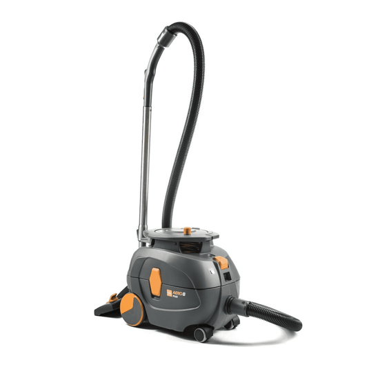Un aspirateur TASKI AERO 8 PLUS, fourni par Diversey Deutschland GmbH & Co. OHG, de couleur grise et orange, est posé à la verticale. Cet aspirateur à réservoir compact et puissant est équipé d'un long tuyau flexible et présente un corps cylindrique doté de grandes roues arrière et de roues avant plus petites, ce qui lui confère une excellente maniabilité et permet un nettoyage efficace. Son fonctionnement est optimisé grâce à la technologie « Flüster », qui garantit un fonctionnement silencieux.