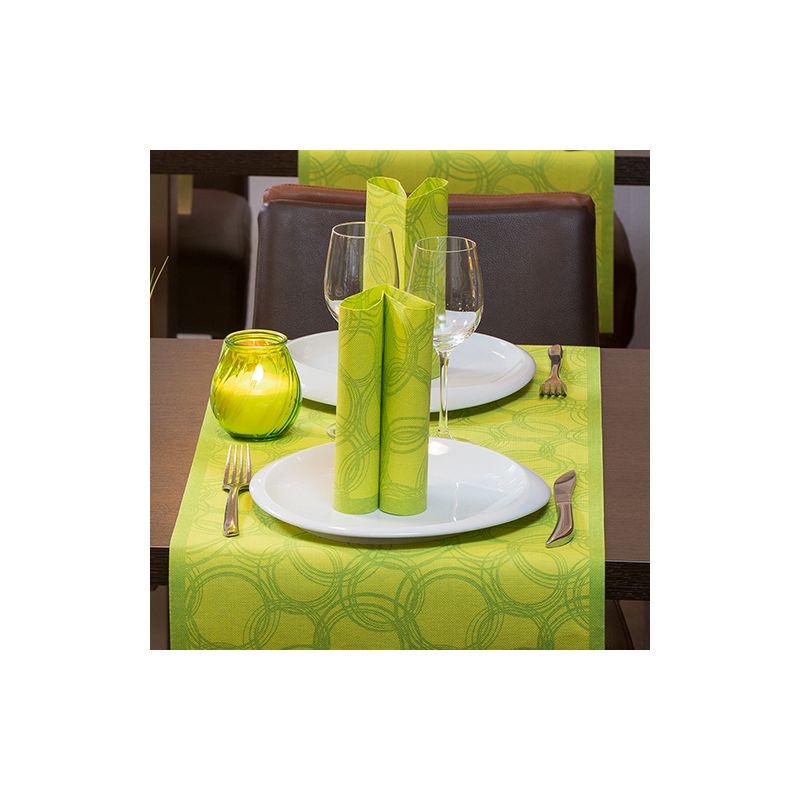 Une table à manger est élégamment dressée pour deux personnes avec des assiettes blanches, des verres à pied et des couverts. Des serviettes vertes sont artistiquement placées sur les assiettes. Un bougeoir vert est placé sur un chemin de table PAPSTAR en tissu mixte PV-Tissue « Collection ROYAL » de PAPSTAR GmbH, dont le motif circulaire ajoute de la sophistication à la scène.