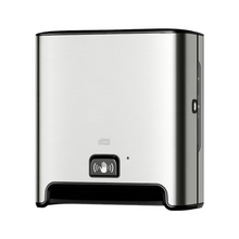 Un distributeur de serviettes en rouleau TORK Tork Matic® 460001 Image Line en acier inoxydable pour montage mural avec capteur H1 | Emballage (1 pièce) avec base noire et symbole d'indication de capteur à l'avant. Ce distributeur, conçu pour la distribution sans contact de feuilles individuelles, présente un design moderne et épuré et utilise des serviettes en rouleau pour garantir une expérience hygiénique.