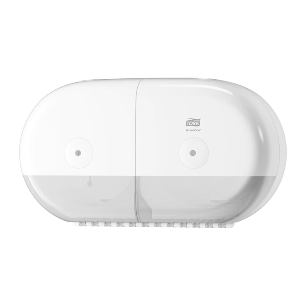Un distributeur double rouleaux Tork SmartOne® 682000 Mini, fabriqué par TORK – Essity Professional Hygiene Germany GmbH, est monté au mur. Ce distributeur blanc, ovale, dispose d'une partie inférieure transparente et est conçu avec son apparence lisse et moderne pour accueillir du papier toilette double rouleaux.