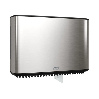 Un distributeur Tork Xpress pour papier toilette mini-jumbo, faisant partie de la Image Line, est élégamment monté au mur. Ce distributeur en acier inoxydable a un design rectangulaire élancé, dont une petite section de papier blanc est visible en bas. La marque « TORK – Essity Professional Hygiene Germany GmbH » est clairement visible sur le devant.