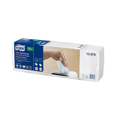 Eine Schachtel Tork Xpressnap® 13670 Extra Soft Blätterdesign Weiße Spenderserviette Premium N4 2-lagig, hergestellt von TORK – Essity Professional Hygiene Germany GmbH, enthält acht Packungen. Die Verpackungsabbildung zeigt eine Hand, die eine Serviette aus dem Spender zieht, was die extra weiche Textur dieser weißen Servietten hervorhebt.