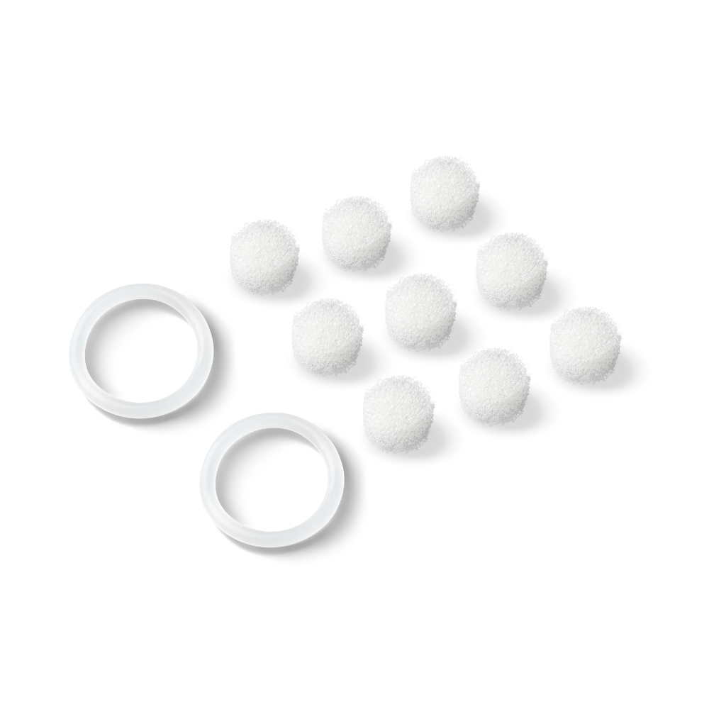 Sur un fond blanc, huit petits objets ronds blancs ressemblant à des boules de coton sont visibles, disposés en formation triangulaire. Deux anneaux en plastique blanc, probablement des filtres de rechange du produit « Beurer FC 40 Filtres de rechange pour nettoyeur de pores | Paquet (20 pièces) » de la Beurer GmbH, sont placés à gauche des boules de coton.