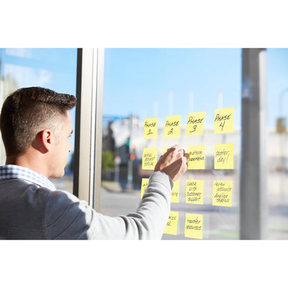 Eine Person benutzt die Post-it® Super Sticky Notes (76 mm x 76 mm, 90 Blatt/Block, 100% PEFC) der 3M Deutschland GmbH, um "Phase 1"-"Phase 4" mit handschriftlichen Projektaufgaben auf einem Glasfenster mit Sonnenlicht und Straßenansicht zu beschriften.