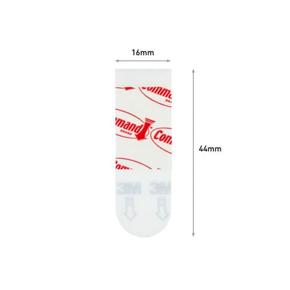 Une seule bande adhésive Command™ Poster-Strip 17024 de 3M Deutschland GmbH est représentée verticalement (16mm x 44mm); le haut est marqué en rouge, le bas est translucide avec le texte gris "3M" - idéal pour fixer des posters sans laisser de résidus.
