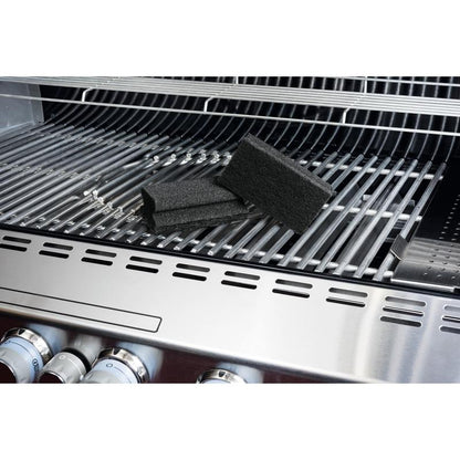 Un tampon à manche Scotch-Brite® de 3M Deutschland GmbH repose sur un gril en acier inoxydable et souligne le nettoyage facile des grilles. Sur la grille, on peut voir les éponges noires, les boutons du gril et le couvercle ouvert.