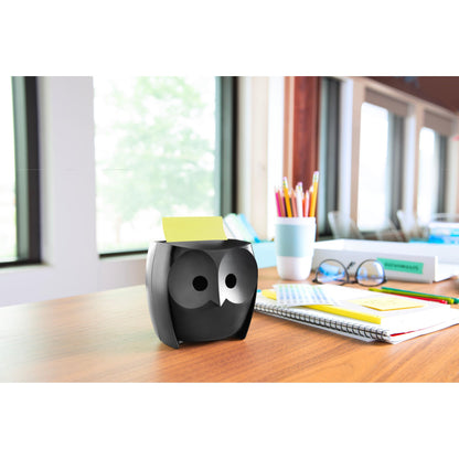 Ein Post-it® Z-Notes Dispenser, Eule, Schwarz der 3M Deutschland GmbH steht auf einem Holztisch mit Notizbüchern, einer Tasse, Buntstiften in einer Tasse und Post-it® Super Sticky Z-Notes (45 Blatt/Block, 2 Blöcke/Packung); große Fenster geben den Blick auf Bäume frei.