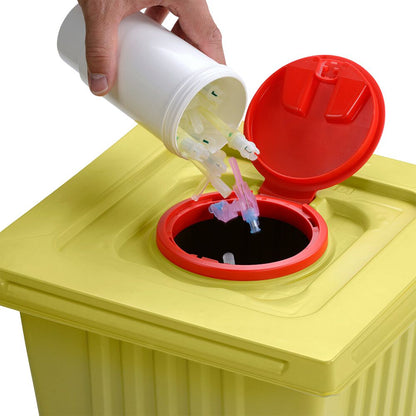 Une main élimine des pointes de seringues usagées d'un conteneur blanc de 12 L Helmut Schwarz GmbH melijekt dans un conteneur jaune pour déchets médicaux avec un couvercle rouge, assurant ainsi une élimination correcte.