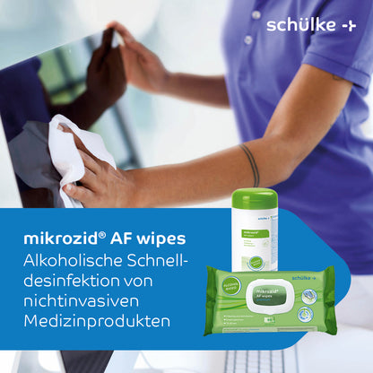 Une personne désinfecte un ordinateur portable avec des lingettes désinfectantes Schülke mikrozid® AF. L'image montre les lingettes désinfectantes pour dispositifs médicaux de Schülke & Mayr GmbH et met en avant la désinfection rapide à base d'alcool des dispositifs médicaux non invasifs. Les informations distinctives de la marque sont visibles à la fois sur un récipient et sur un paquet de lingettes.