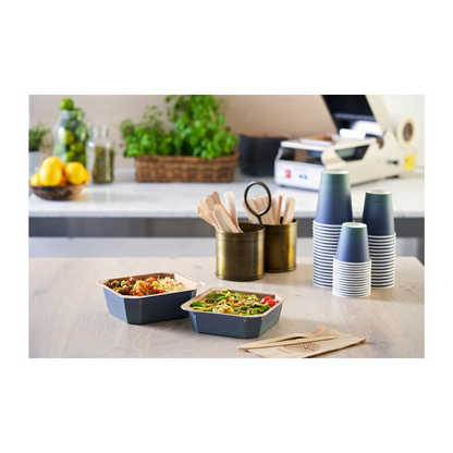 Sur la table, il y a deux bols à emporter, flanqués de gobelets à café Duni Urban PAP/PLA empilés de Duni GmbH, des couverts en bois dans un support et des serviettes. Des citrons, des verres et des herbes en arrière-plan contribuent à l'ambiance durable de cette zone de préparation des repas.